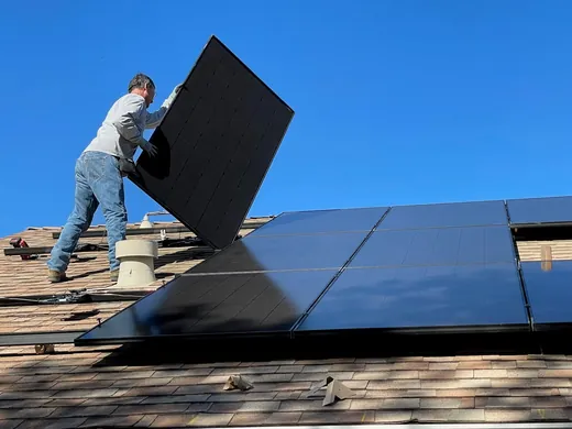 Monteur setzt ein Solarmodul auf die Unterkonstruktion