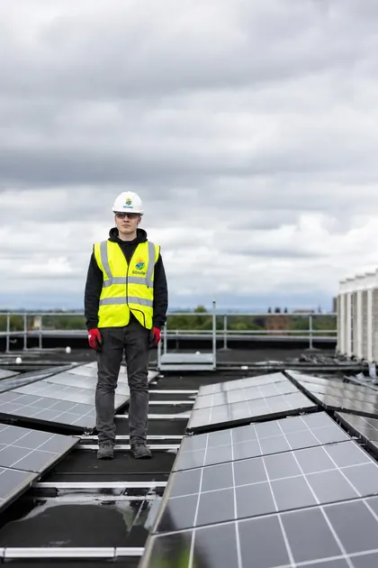 Monteur von GOsolar in Arbeitskleidung auf einer fertiggestellten Solaranlage